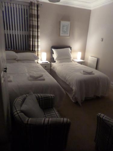 a bedroom with two beds and a chair in it at Nathans Guest House in Blackpool