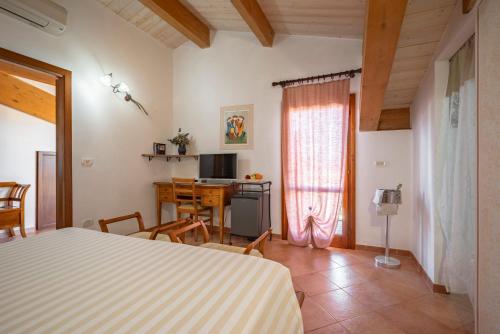 a bedroom with a bed and a table and a desk at Lola Piccolo Hotel e Appartamenti in Marina di Grosseto