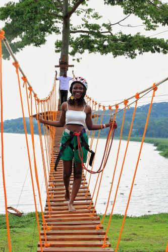 a woman crossing a suspension bridge over a body of water at Divine Resort & Spa in Kampala