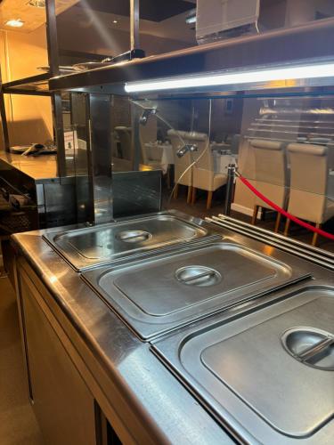 a stainless steel counter in a kitchen with tables and chairs at The Lawton in Blackpool