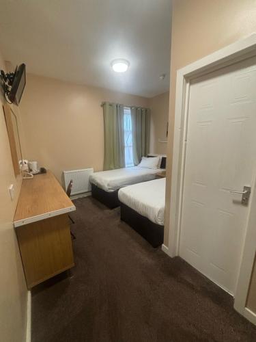 a small hotel room with two beds and a door at The Lawton in Blackpool
