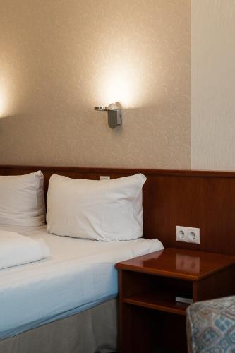 a hotel room with a bed with white pillows and a table at Trip Inn Parkhotel Bad Ems in Bad Ems