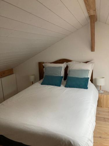 une chambre avec un lit blanc avec des oreillers bleus dans l'établissement CHALET ARIZONA - AU COTTAGE DU MEDOC - Proche de BORDEAUX, à Saint-Aubin-de-Médoc
