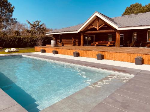 a swimming pool in front of a house at CHALET ARIZONA - AU COTTAGE DU MEDOC - Proche de BORDEAUX in Saint-Aubin-de-Médoc