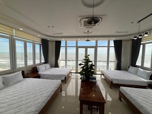 a room with three beds and a table and windows at Khách Sạn A68 in Vung Tau