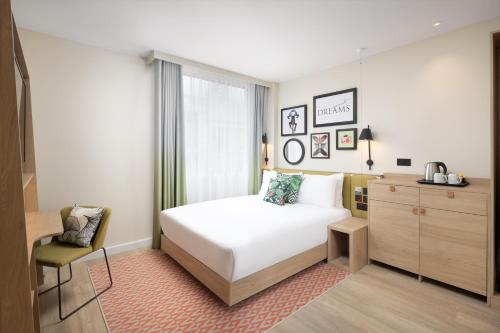 a bedroom with a white bed and a chair at Hampton By Hilton London Old Street in London