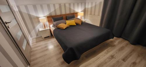 a bedroom with a black bed with two yellow pillows at Apartament Czerwone Maki in Krakow