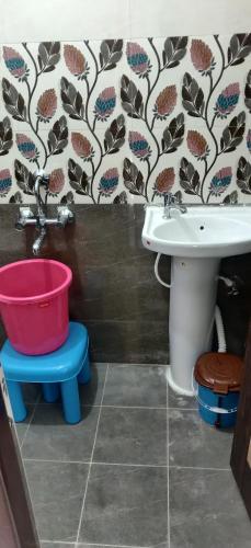 a bathroom with a toilet and a sink and a bucket at Castle Hebbal Service Apartments in Bangalore