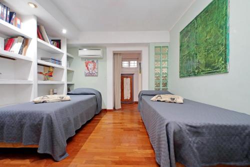 ローマにあるAppartamento Centraleのベッド2台と本棚付きの部屋