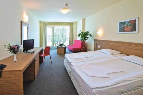 ein Hotelzimmer mit einem Bett und einem Schreibtisch mit einem Computer in der Unterkunft Jeravi Club Hotel - All Inclusive in Primorsko