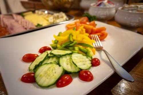 a white plate with cucumbers and tomatoes and a fork at Mountain Lodge in Grächen