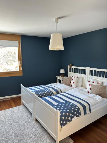 1 dormitorio con cama blanca y pared azul en Pineview Waldhaus, en Flims