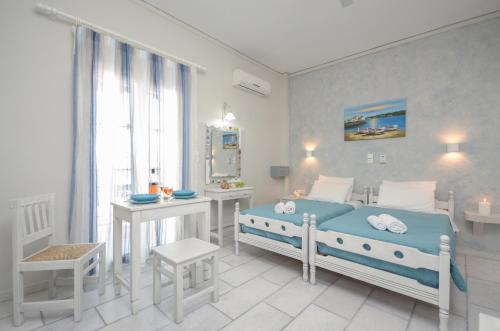 a white bedroom with a bed and a desk at Sofi pension in Naxos Chora