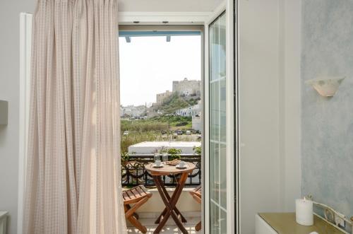 a room with a balcony with a table and a window at Sofi pension in Naxos Chora