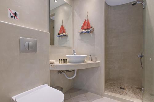a bathroom with a sink and a toilet with two sailboats on the wall at Sofi pension in Naxos Chora