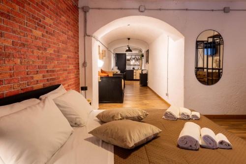 a bed with three pillows and a brick wall at DOMUS LAURA Rione MONTI in Rome