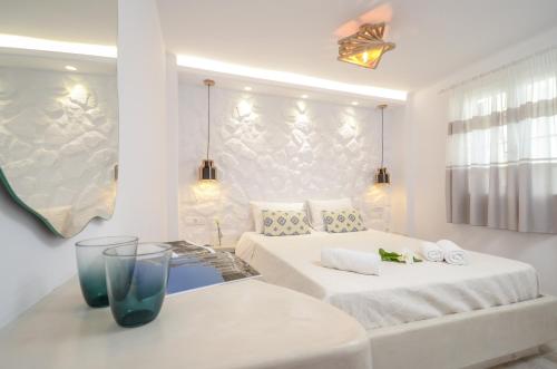 a white bedroom with two beds and a table at Sofi pension in Naxos Chora