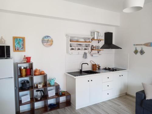 een witte keuken met een wastafel en een koelkast bij La casetta di rosario mondello in Palermo