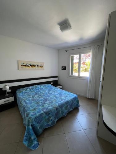 a bedroom with a bed with a blue comforter and a window at Casa Vacanze con piscina - Caorle in Porto Santa Margherita di Caorle