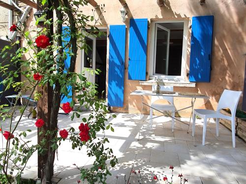 a patio with a table and chairs and red roses at Les pieds en éventail in Lignairolles