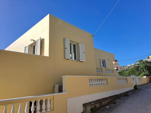 a yellow building with windows and a balcony at ENDLESS VIEWS PANTELI LEROS in Panteli