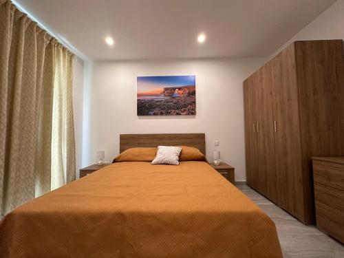 a bedroom with a bed with a orange bedspread at La Bella Guesthouse in St Julian's