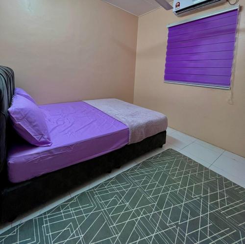 a small bedroom with a purple bed and a window at Nuha's Homestay Teluk Intan in Teluk Intan