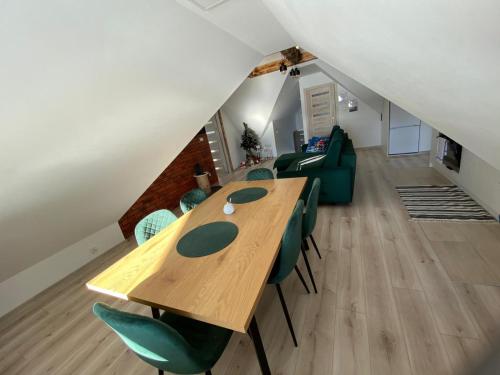a dining room with a wooden table and green chairs at Apartament Nasze Poddasze in Ciche