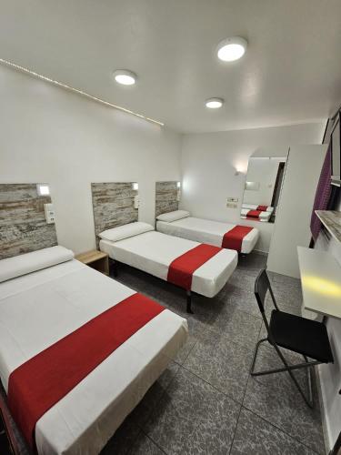 a room with three beds and a mirror at Hostal Las Vegas in Madrid