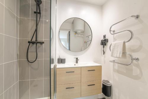 ein Badezimmer mit Dusche, Waschbecken und Spiegel in der Unterkunft Blackwood-parking privé gratuit in Villeurbanne