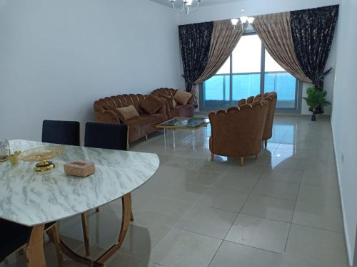 a living room with a table and chairs at 30 R1 Single 1 Master Room in 3 bedroom apartment with attached washroom and balcony with fantastic sea view 30 R1 غرفة مفردة 1 ماستر في شقة 3 غرف نوم مع حمام ملحق وشرفة بإطلالة رائعة على البح in Ajman 