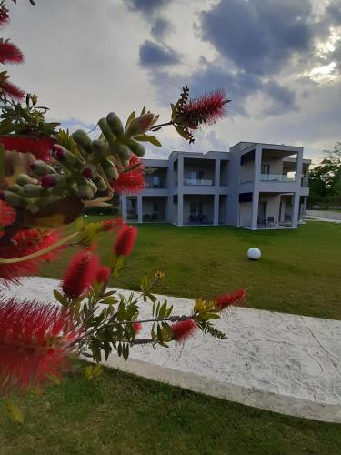a large white building with a yard with flowers at Olympus Pantheon Luxury Rooms in Plaka Litochorou