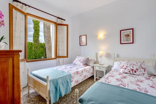 a bedroom with two beds and a window at Casa La Palmera in Cala Figuera