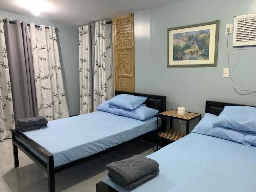 a room with two beds with blue pillows at Altheos Place Romblon Cottage 2 in Romblon