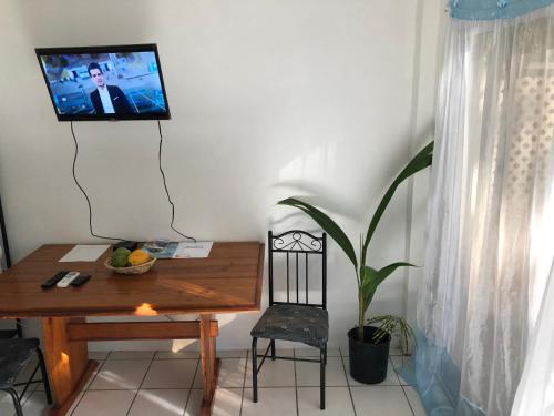 a room with a table and a chair and a television on a wall at Diamondview Cherry Studio in Soufrière