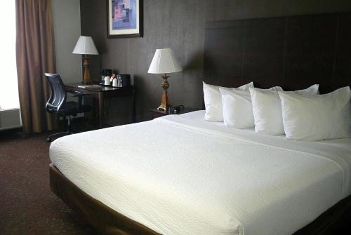 a large bed with white pillows in a hotel room at Wyndham Garden Detroit Metro Airport in Romulus