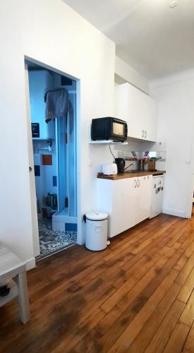 Il comprend une cuisine avec des murs blancs et du parquet. dans l'établissement Studio Paris 13 Quartier Butte-aux-Cailles, à Paris