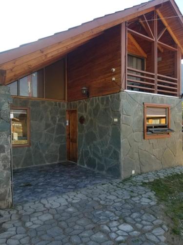 a large stone house with a wooden roof at Aysen Bike Cabañas in Puerto Aisén