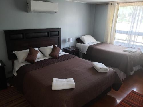 a hotel room with two beds and a window at Aysen Bike Cabañas in Puerto Aisén