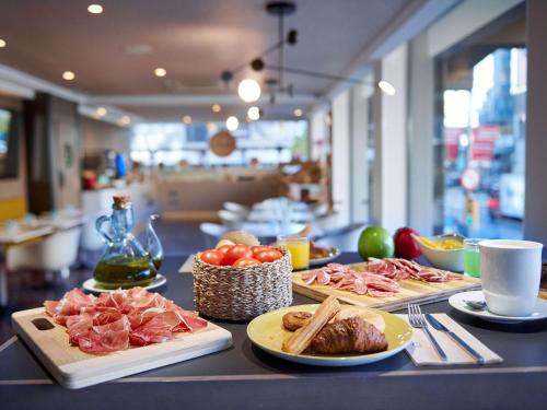 einen Tisch mit Teller mit Lebensmitteln auf einer Theke in der Unterkunft Mercure Barcelona Condor in Barcelona