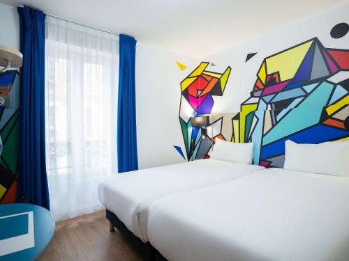 パリにあるイビス スタイルズ パリ メーヌ モンパルナスのベッドルーム1室(壁に絵画が描かれたベッド1台付)