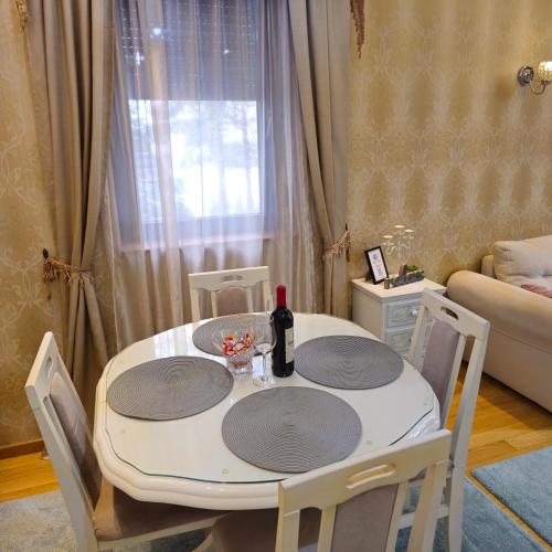 a dining room table with a bottle of wine on it at Apartman Pineta in Zlatibor