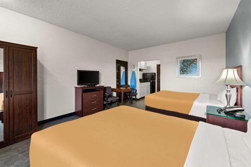 Habitación de hotel con 2 camas y TV de pantalla plana. en Suburban Studios Kansas City Airport North en Platte City