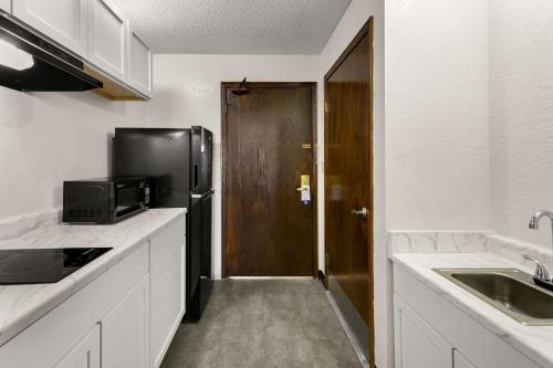 a kitchen with a black refrigerator and a sink at Suburban Studios Kansas City Airport North in Platte City