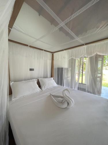 a large white bed in a room with curtains at Bokka Almeida in Hikkaduwa