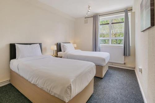 two beds in a room with a window at The Serene Flat W Free Street Parking in Hackbridge