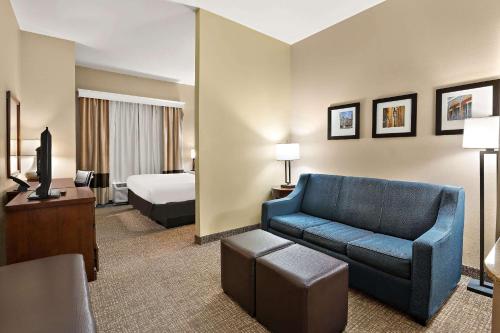 a hotel room with a blue couch and a bed at Comfort Inn New Orleans Airport South in Saint Rose