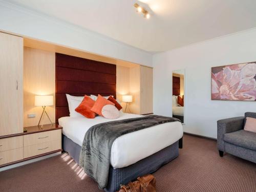 ein Hotelzimmer mit einem großen Bett und einem Stuhl in der Unterkunft Mercure Albury in Albury