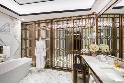 a bathroom with a tub and a robe on a wall at Waldorf Astoria Kuwait in Kuwait