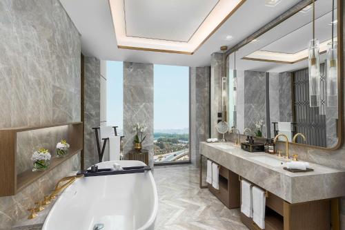 a bathroom with a large tub and a large window at Waldorf Astoria Kuwait in Kuwait